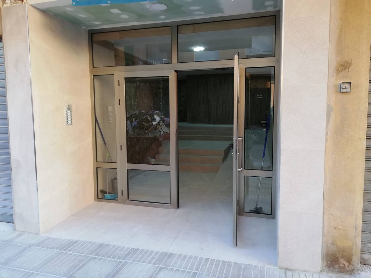 Entrada de comunidad renovada con carpintería de aluminio y vidrio