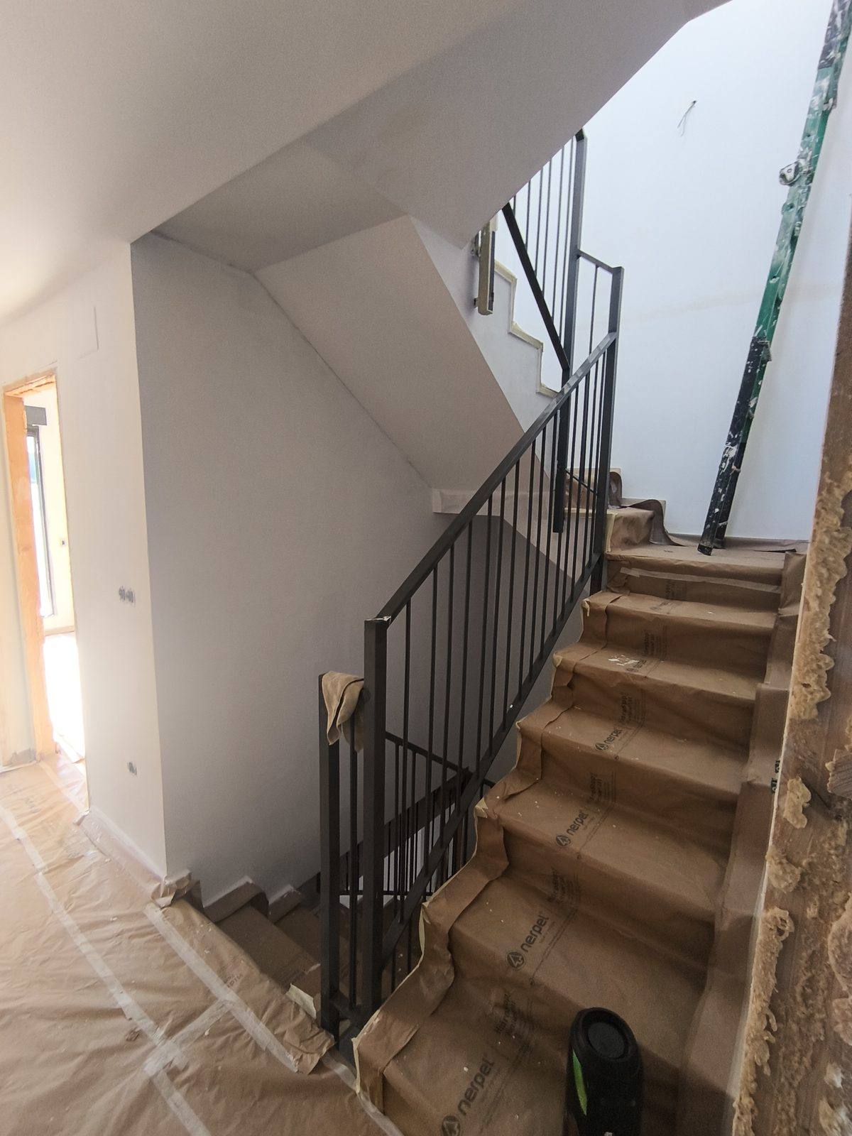 Escalera interior con las paredes en gris de obra, antes de pintar
