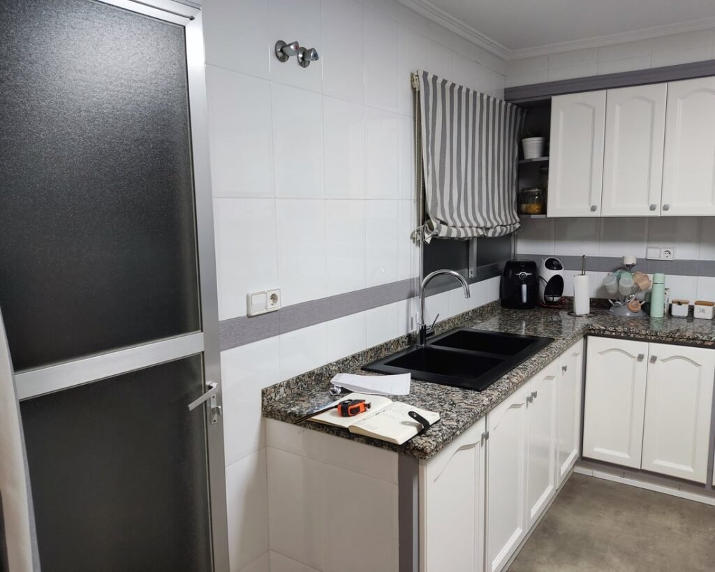 Cocina con muebles blancos y encimera de granito, antes de la reforma
