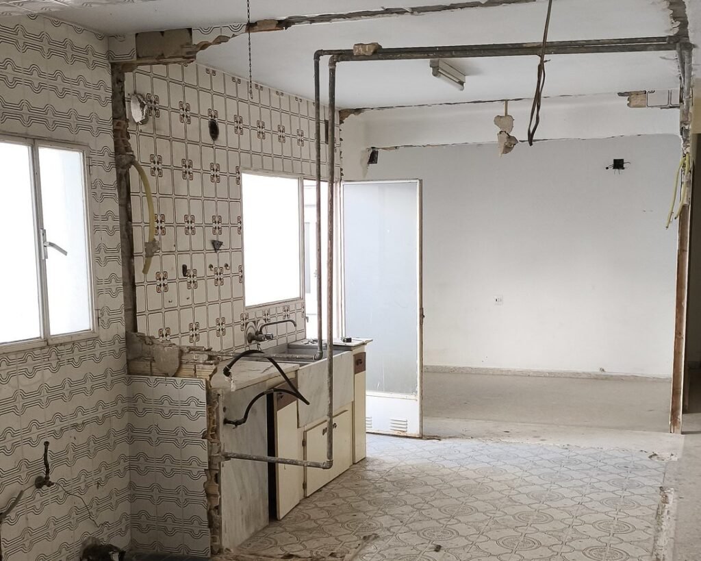 Cocina y salón de una vivienda en Silla durante la demolición, con el azulejo antiguo y las instalaciones a la vista