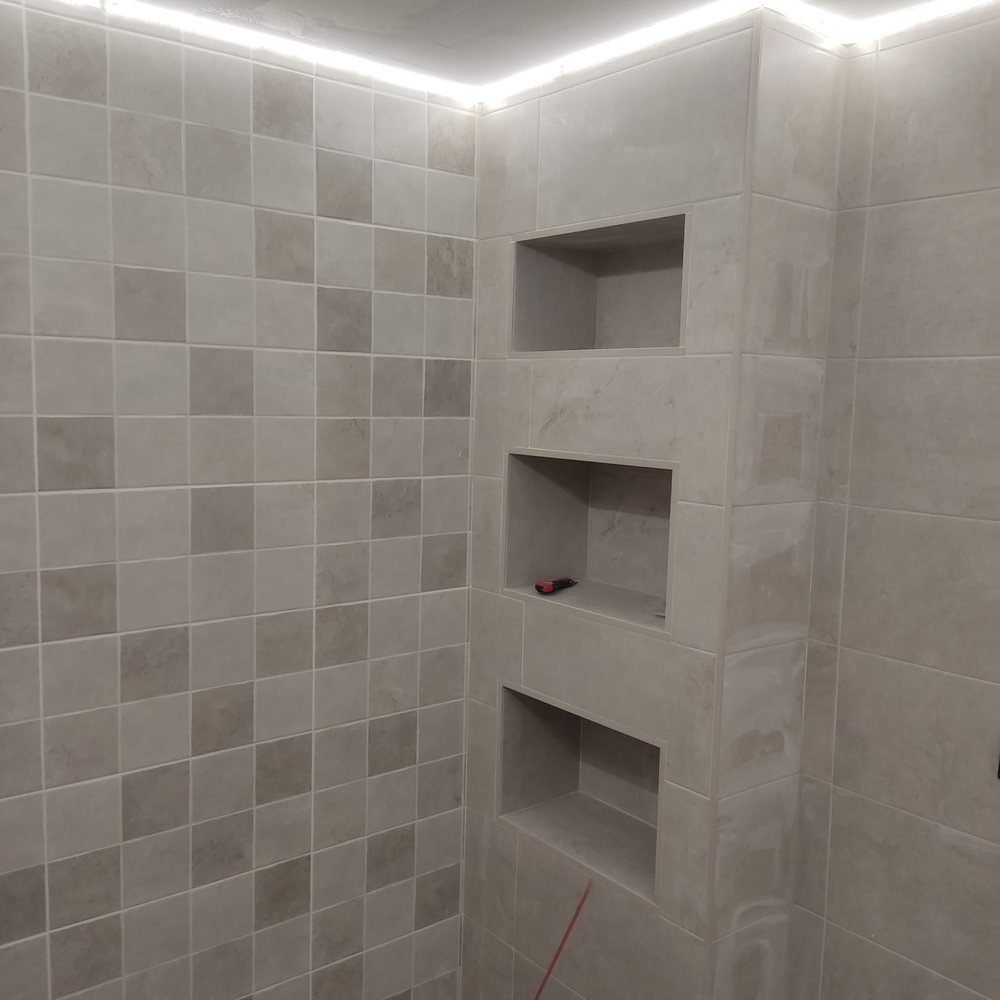 Tres hornacinas alicatadas en la pared de la ducha, con luz LED perimetral en el techo