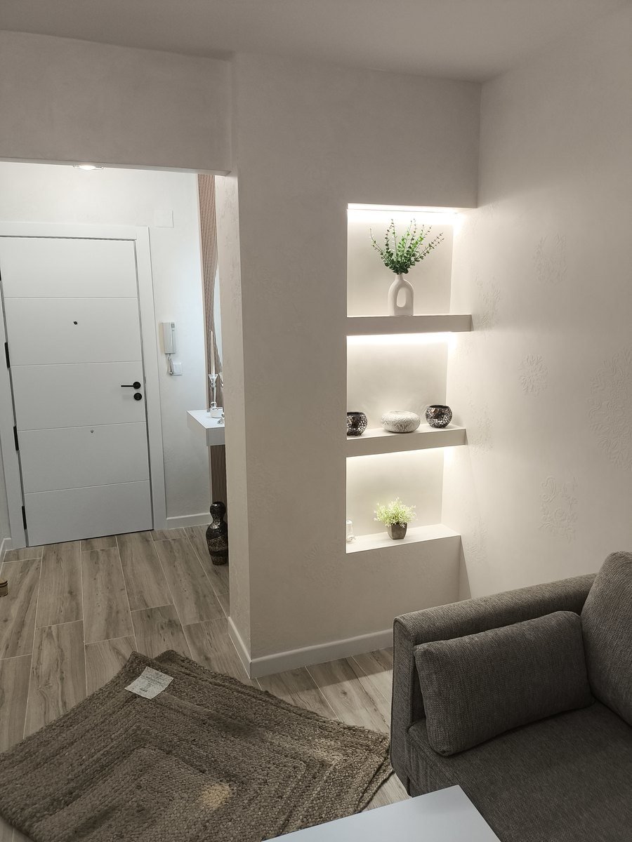 Las mismas hornacinas terminadas, pintadas en blanco y con luz LED, decoradas con plantas y jarrones en el salón